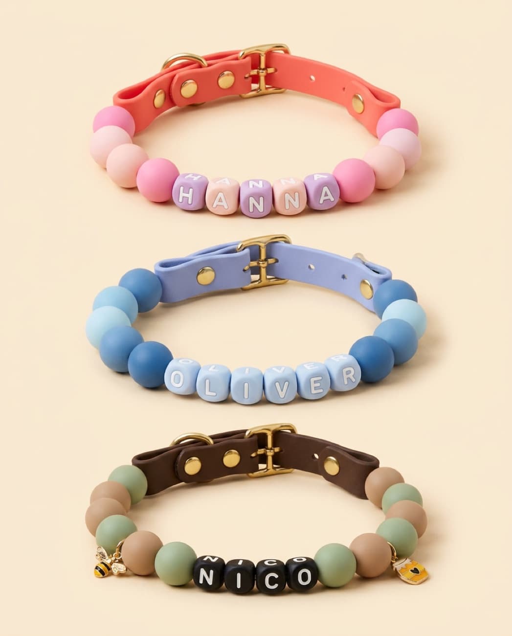 Four Cukie Crew collars in pink, blue, sage and butter-yellow beads, stacked together